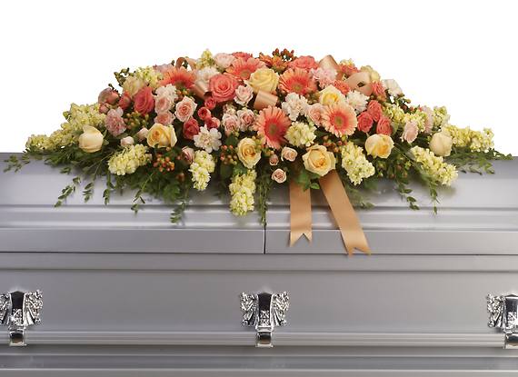 WARMEST REMEMBRANCE CASKET SPRAY - This gorgeous casket spray featuring peach, pink and coral roses is an expression of great love and a beautiful final farewell to a lost loved one.  The beautiful bouquet includes peach roses, light pink spray roses, coral spray roses, light orange gerberas, light orange carnations, light yellow stock and peach hypericum, accented with satin ribbon and assorted greenery.