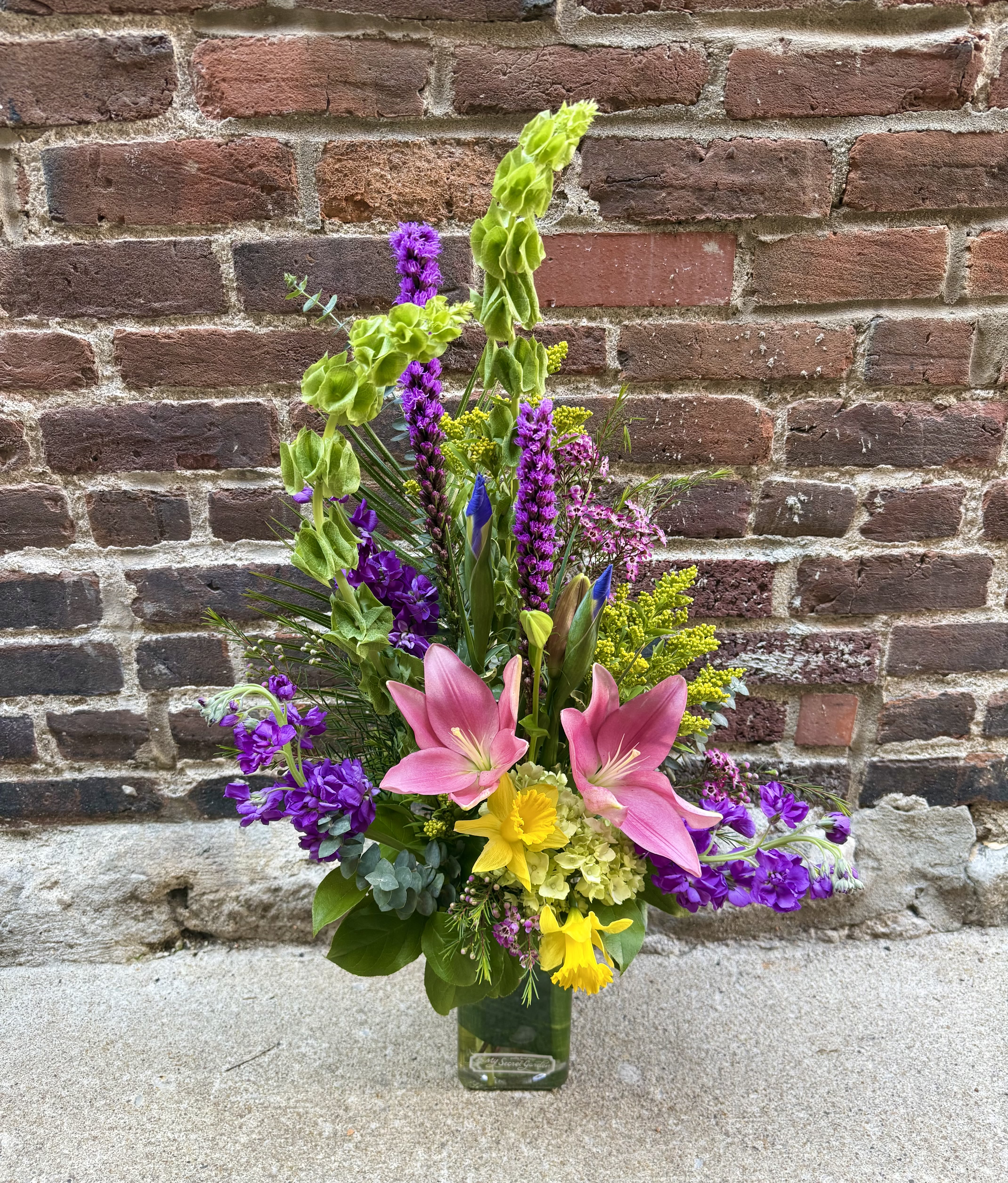 Unique Spring - This stunning and unique arrangement showcases the Spring season with a burst of breathtaking flowers. Including beautiful Hydrangea, Liatris, Lilies, and Iris, these bright flowers are sure to bring happiness and delight this spring season. Perfect for any office or home space.