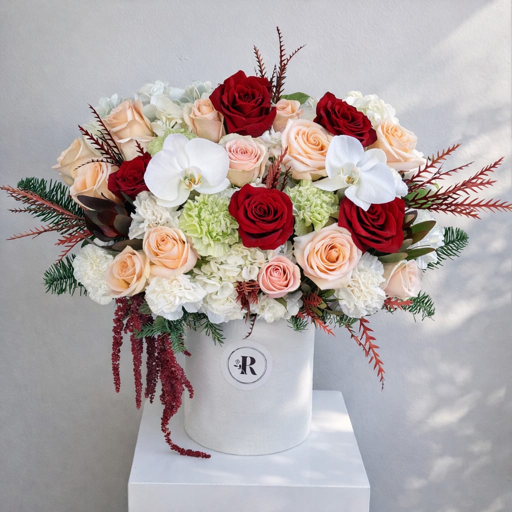 Angela -D - Rich red roses are paired with delicate blush and peach roses, creamy white hydrangeas, and graceful white orchids.  DELUXE size is in the photo. 