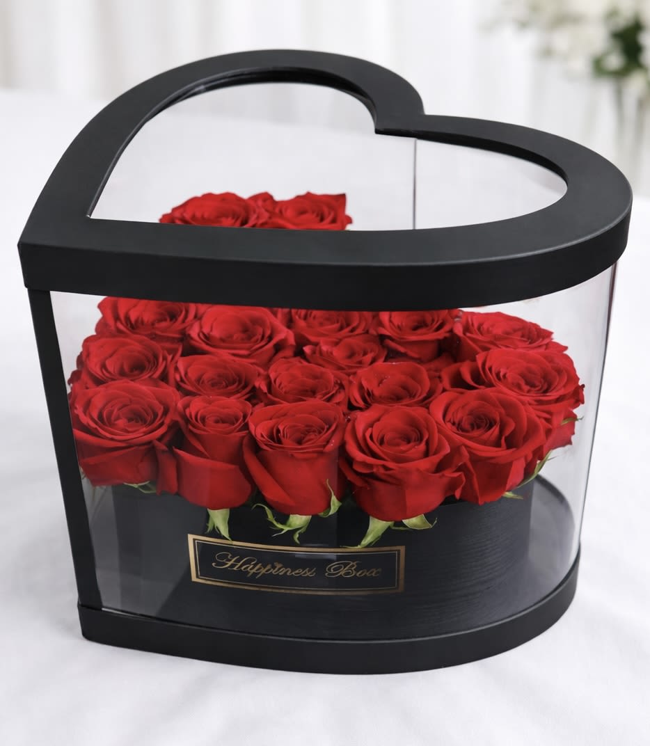 Luxury Acrylic Heart Rose Box - This structured heart-shaped box features fresh roses beautifully displayed inside a transparent acrylic frame, creating a sleek and elevated presentation. Its clean lines and modern silhouette enhance visibility while maintaining a romantic and luxurious aesthetic.  Designed in a medium-to-large structured heart format, this piece offers a fuller visual impact compared to traditional heart boxes.  Available in two box color options: • White • Black  Rose color may vary based on availability to ensure the freshest and highest-quality selection at the time of your order.  Perfect for anniversaries, romantic surprises, birthdays, or elegant celebrations.  Handcrafted by AMORE in Nashville, Tennessee. Available for local flower delivery in Nashville and surrounding areas.