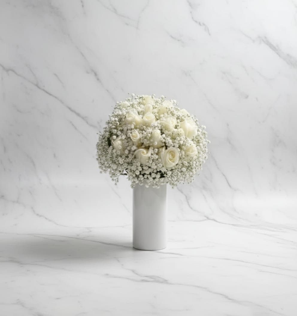 Snowfall Serenity - Soft, pure, and effortlessly elegant. this breathtaking arrangement features fresh white roses surrounded by delicate clouds of baby's breath, beautifully arranged in a sleek white decorations because it is bridal bouquet. Suave, puro y elegantemente sencillo. Este impresionante arreglo presenta rosas blancas frescas rodeadas de delicadas flores aliento de bebe, bellamente puestas en un elegante decoraciones blancas por que es un ramo de novias.
