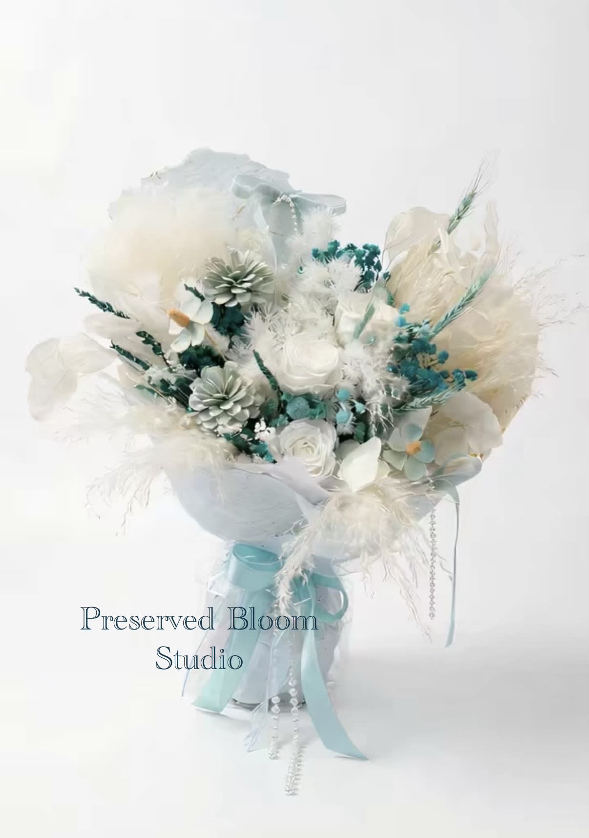 Aqua Whispering - This is a fresh and natural mint green and white immortal flower/dried flower bouquet. The color is soft and the packaging style is fashionable, which is very suitable for modern decoration and gifts. Describe Flowers: Roses are matched with small white daisies (or chamomile), a large amount of white fluffy hay and green wheat spike-shaped dried flowers. Color matching: mainly soft mint green and white, dotted with natural green, creating a quiet and comfortable atmosphere. Green represents life and vitality, and white symbolizes purity and calmness. Packaging: It is wrapped in multi-layer light light green transparent organza or tulle, which is a popular Korean ins style design, which looks fluffy and dreamy. Decoration: The bouquet is also decorated with pearl beaded pendants and light blue ribbons, adding a sense of exquisiteness. Meaning and use Meaning: Mint green symbolizes recovery, growth, calmness and health. White roses represent purity and respect. The overall meaning is friendship or love that never fades, as well as good wishes. Occasion: Because it is an eternal flower material, it can be stored for a long time (usually sustainable for 1 to 2 years), which is very suitable as a graduation gift, birthday gift, anniversary or any occasion that needs to express lasting blessings. 