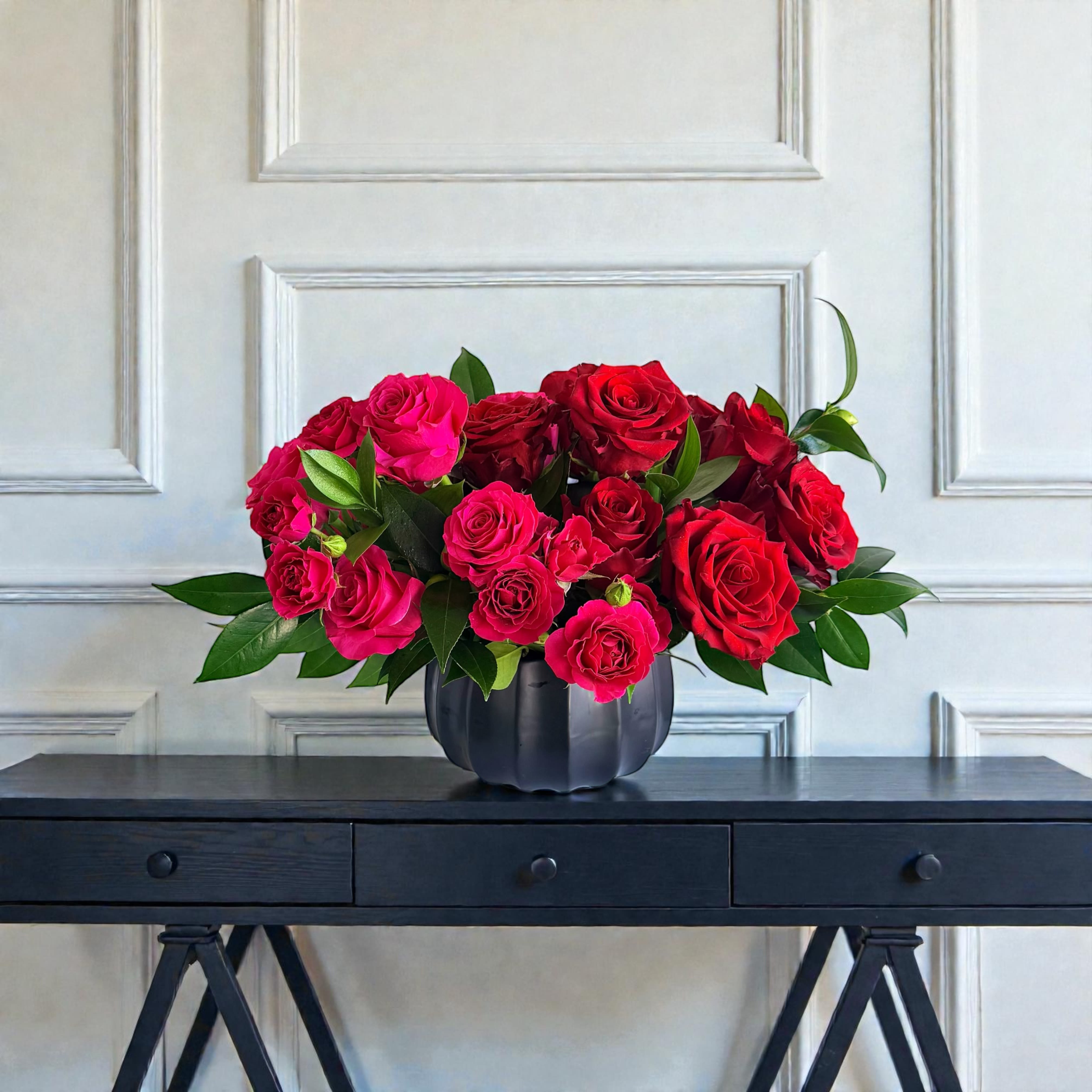 Red and pink roses arranged in a black vase