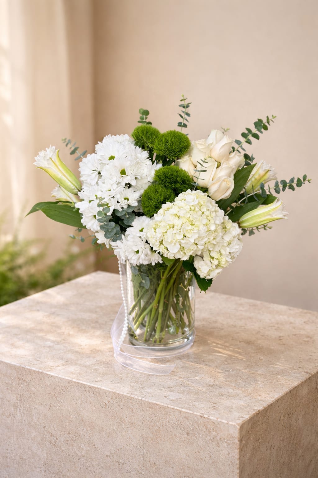Opal Bloom  - A refined white arrangement featuring hydrangeas, roses, lilies, and fresh greenery in a clear glass vase. Elegant, soft, and effortlessly timeless.