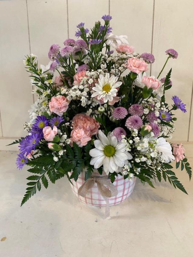 Pink Picnic - This cute arrangement has assorted purple daisies, carnations and misc. filler flowers. All in a keepsake pink and white ceramic basket.