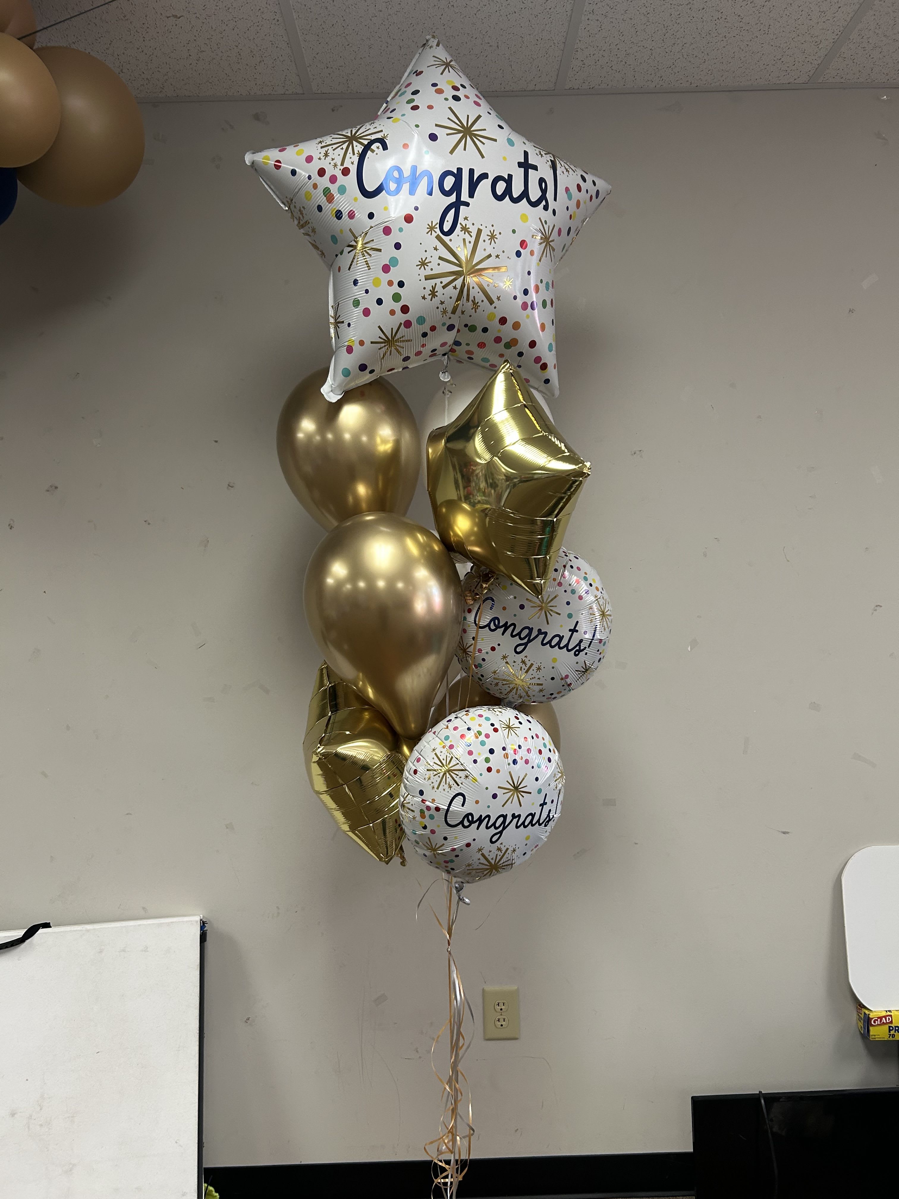 Cluster of gold and printed congratulatory balloons with a star balloon