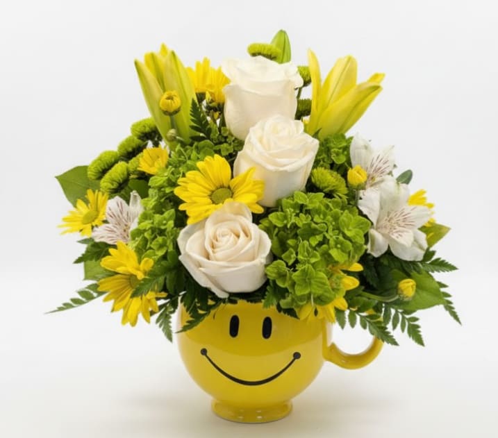 Sunny Smiles - Bright, cheerful, and guaranteed to lift spirits, Sunny Smiles is a joyful arrangement designed to spread happiness. This playful bouquet features elegant white roses, vibrant yellow daisies, cheerful yellow lilies, and delicate alstroemeria, all surrounded by fresh seasonal greenery. The flowers are arranged in a fun yellow smiley-face mug, making it a gift that continues to bring smiles long after the flowers are gone.