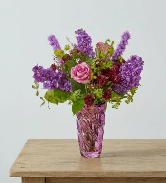 Garden Mist - Beautiful purple flowers of many types come together in this gardeny arrangement, designed in a gorgeous Lavender glass vase. 