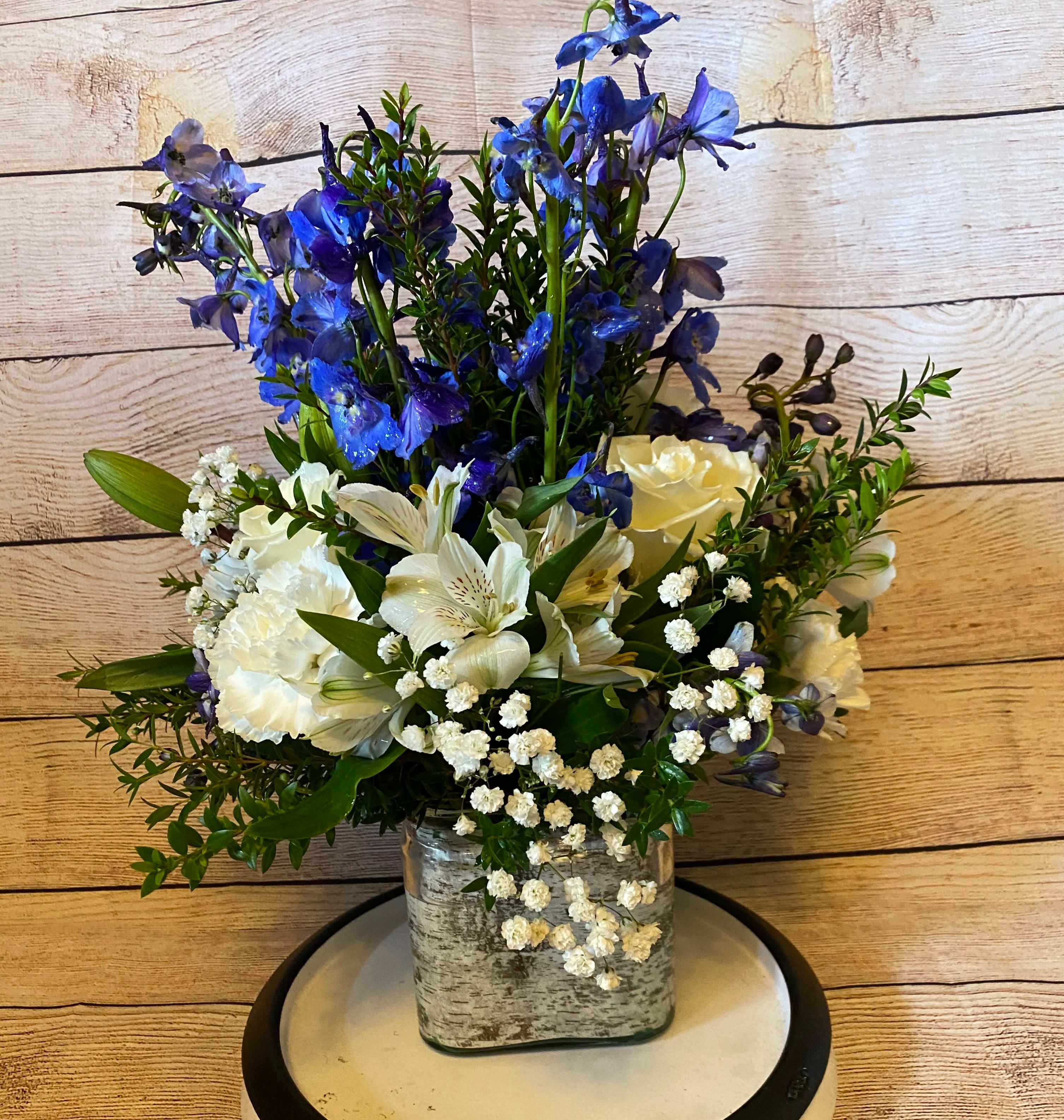 Blue and white floral arrangement in a square glass vase