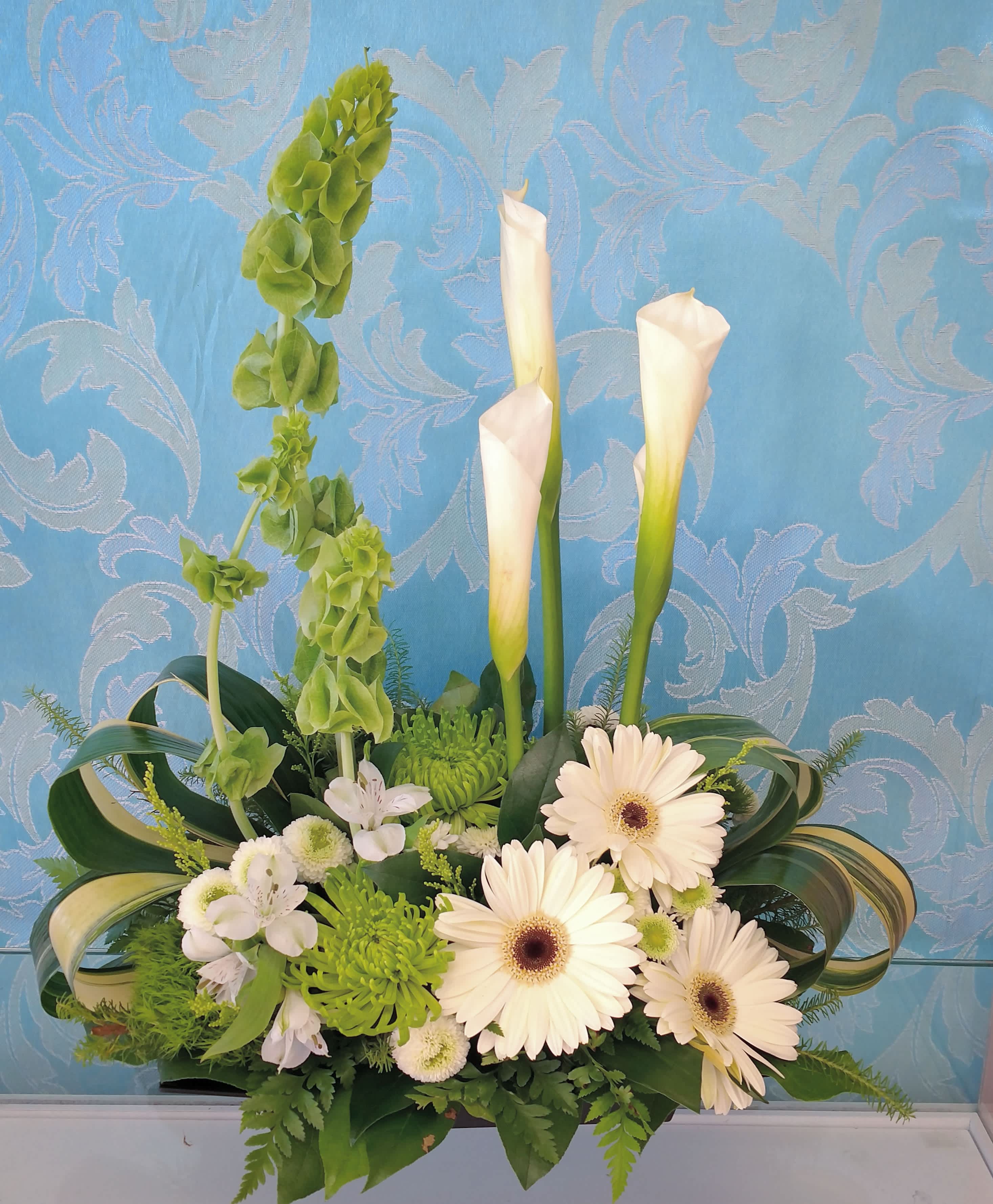 Ireland Bells Bouquet - Fresh green and white look with bells of Ireland, white calla lilies,  white Gerber daisies,  green mums and other accent flowers that will compliment the levels of The T leaf in this unique design.