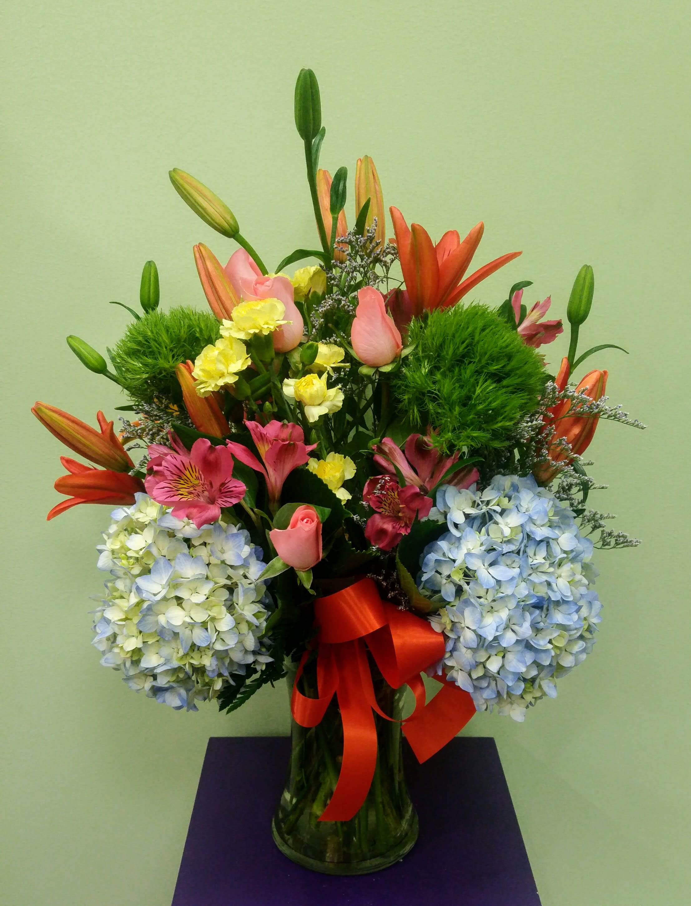 Spring Fever - If you're in the spring mood, send this magnificent bouquet full of spring colors. It includes gorgeous blue hydrangea, bright orange lilies and brilliant pint roses. There are other vivid colors in the arrangement as well, such as green, hot pink and yellow. A massive arrangement that will leave them speechless.