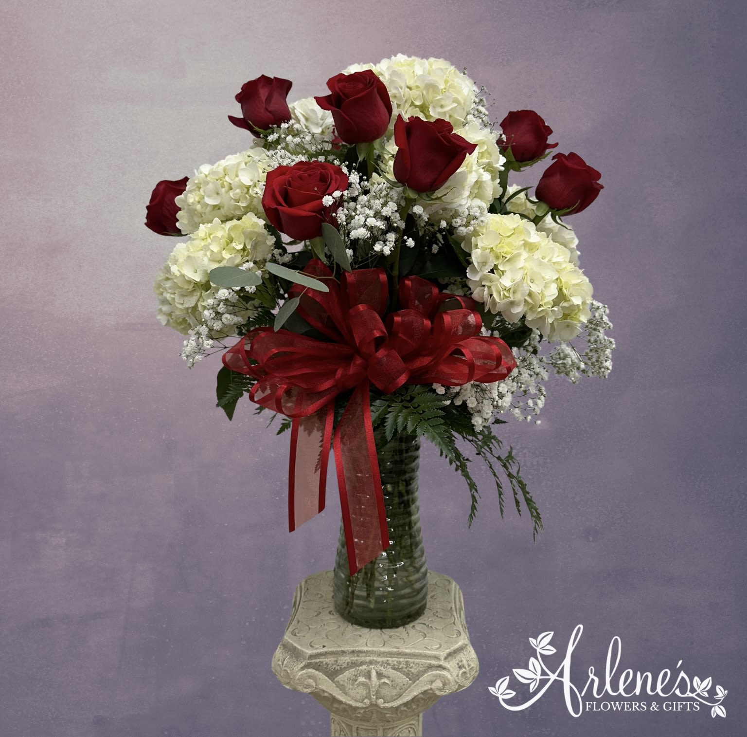 In The Midst Of Love  - This stunning arrangement of roses and hydrangeas is sure to make you fall in love all over again. 12 red roses with hydrangeas, greenery and filler. 