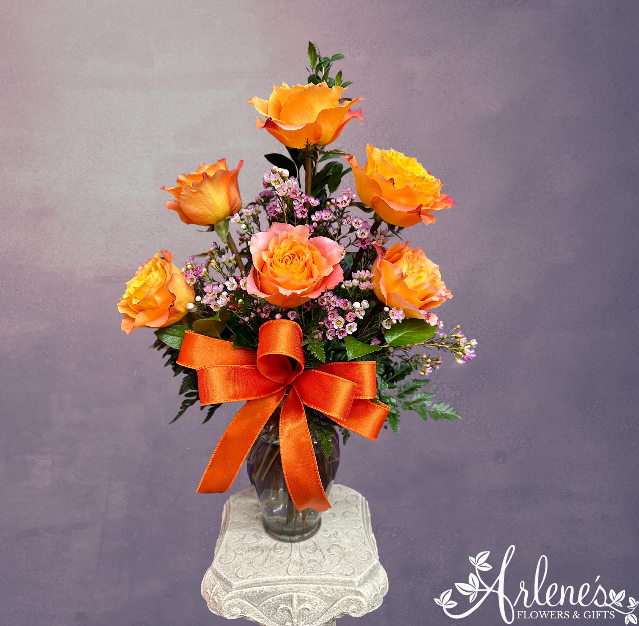 Half Dozen Sweet Orange Roses - A shop favorite, every designer loves the orange roses. They tend to smell the best and open the biggest! Six orange roses, with filler and greenery in a vase with a bow.