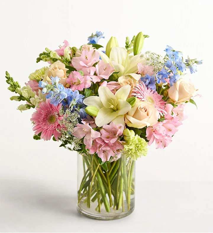 Pastel Garden Celebration - Soft, romantic, and full of seasonal charm, our Pastel Garden Celebration arrangement features a lush blend of premium blooms in delicate shades of blush, lavender, peach, and sky blue. Designed in a clear glass vase with fresh greenery accents, this elegant centerpiece brings a light, airy feel—perfect for birthdays, Mother’s Day, or simply brightening someone’s day.