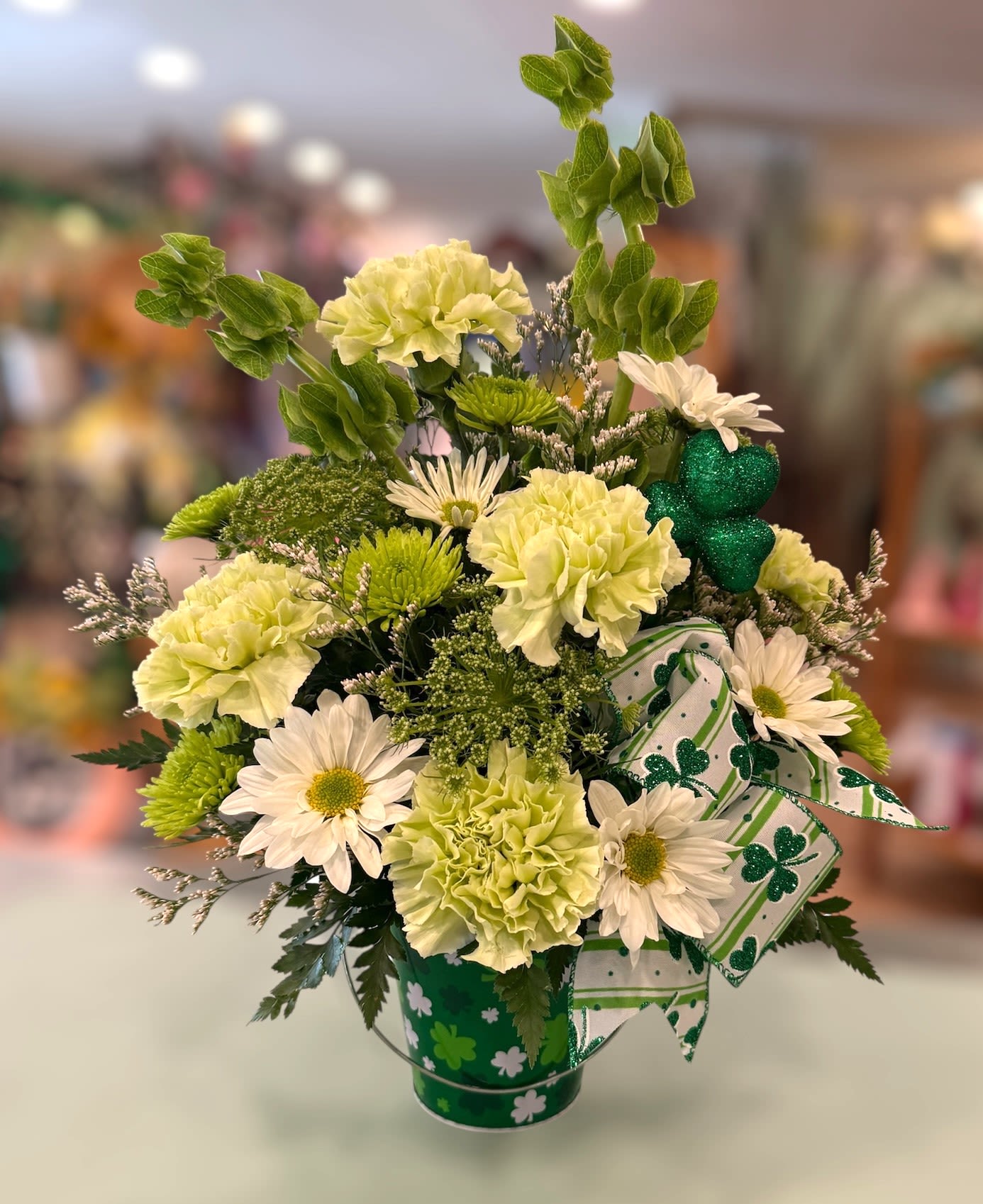 Luck Of The Irish (LOI) - This festive design is perfect for celebrating St. Patty's Day! Filled with Bells of Ireland, Daisies', carnations and more in a tin container.