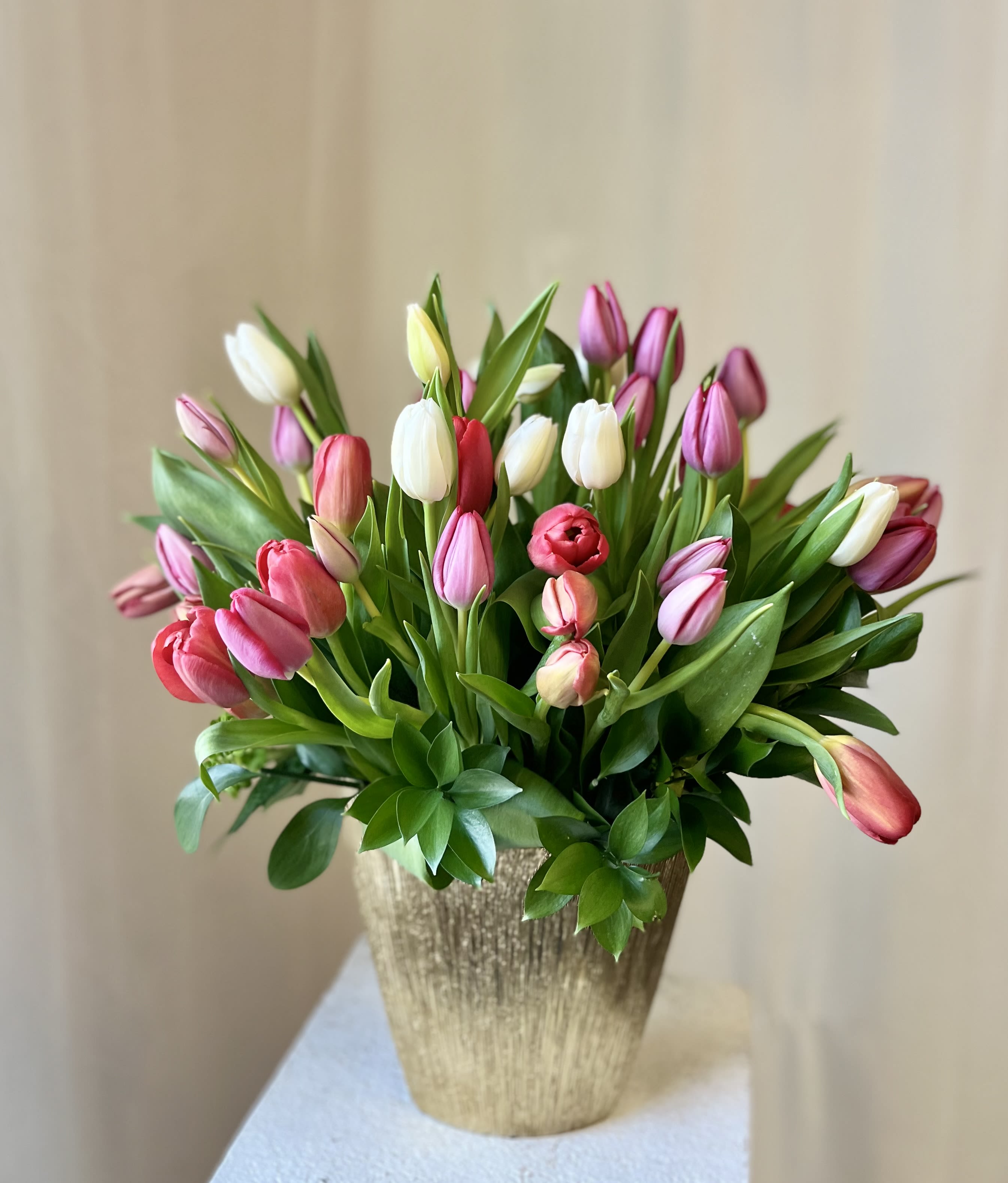 Bouquet of pink, white, and red tulips in a gold vase