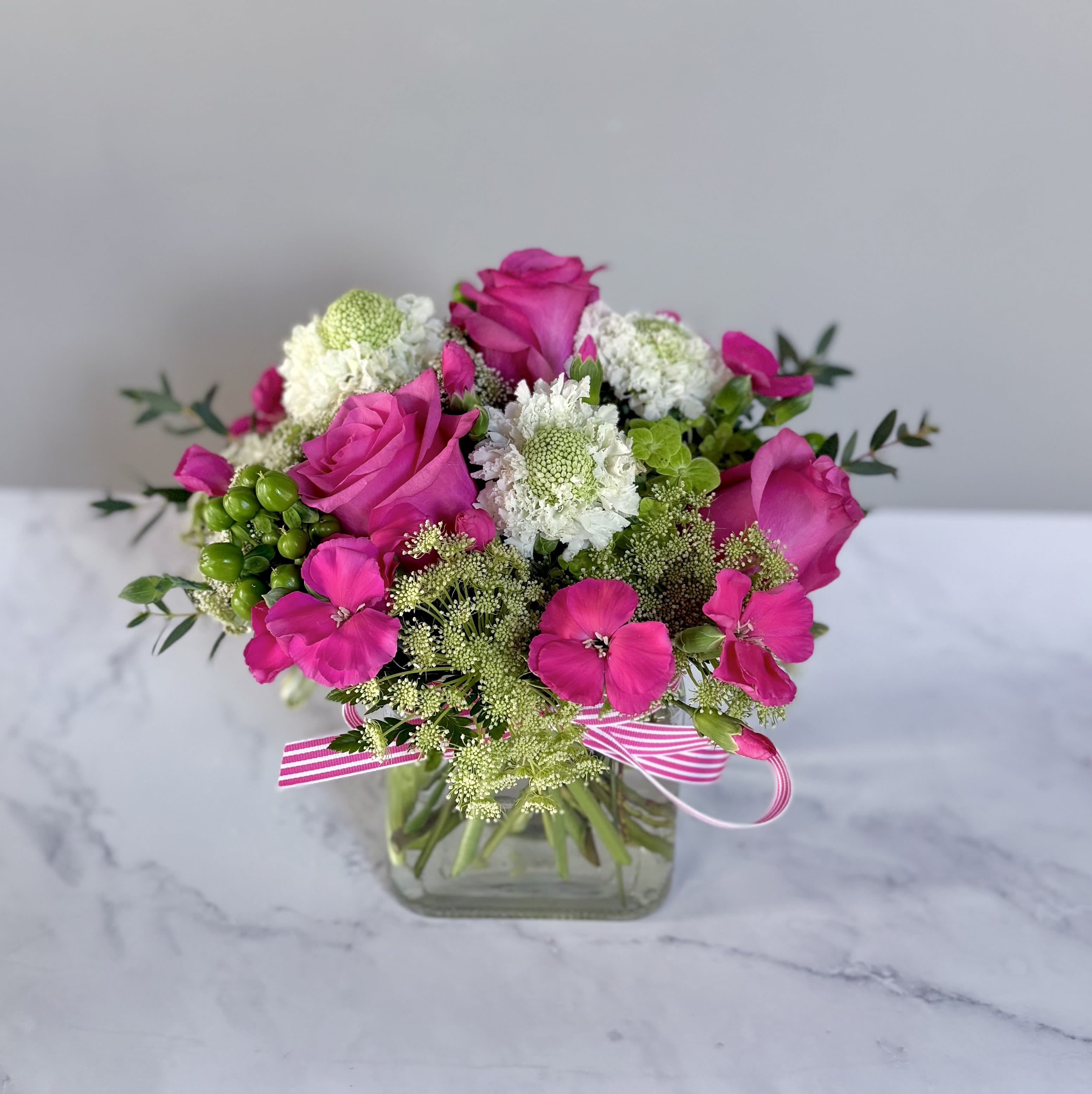 Hot pink and green cube arrangement  - A 5” by 5” cube filled with a green hydrangea, queen Anne’s lace, hot pink roses, hot pink Solomios, green berries and white scabiosa. 