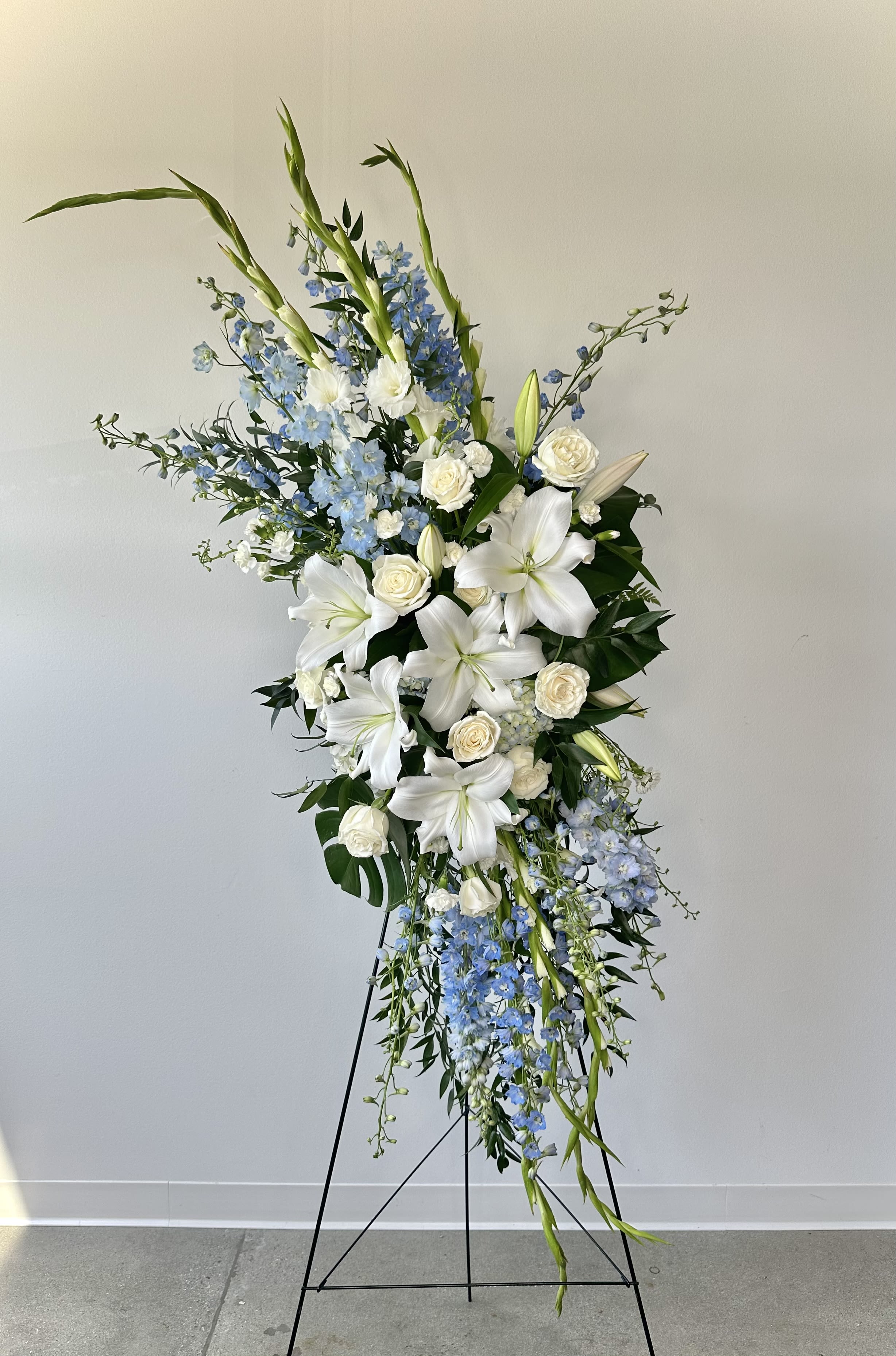 Tall white and blue floral standing arrangement on a black easel