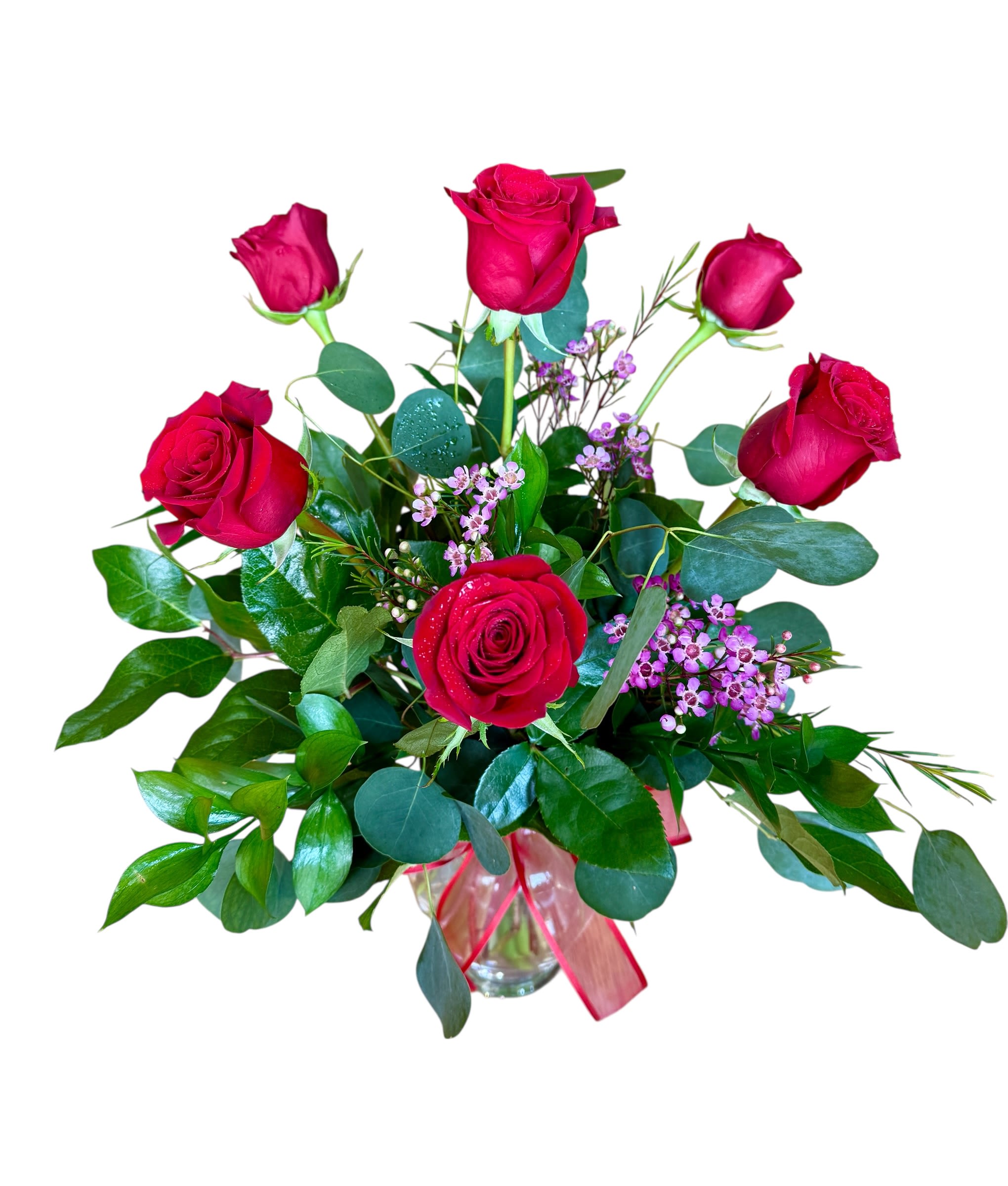 Vase arrangement of red roses with small pink filler flowers in a clear glass vase with red ribbon