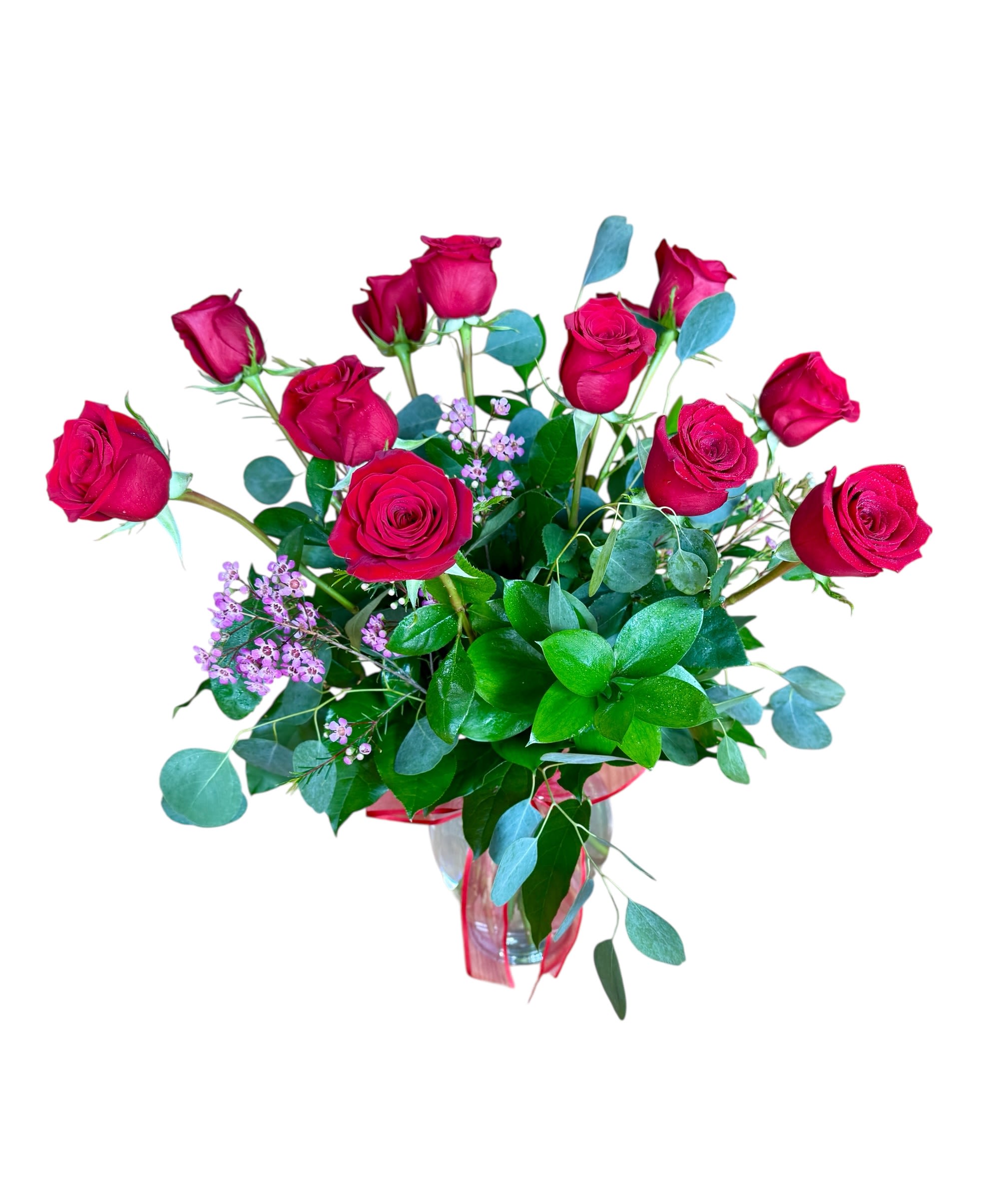 Arrangement of red roses with small pink blooms in a clear glass vase with a red ribbon