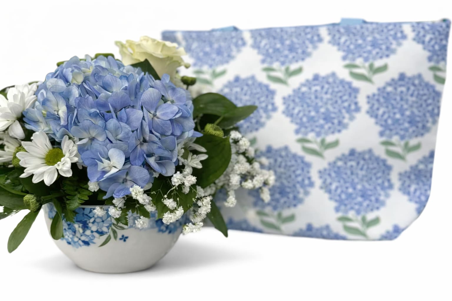 Token of Appreciation Bouquet w/ Lunch Bag - Token of Appreciation Bouquet with hydrangea Lunch Bag Arrangement is designed in a ceramic contaiver with blue hydrangea, White daisys, roses and baby's breath