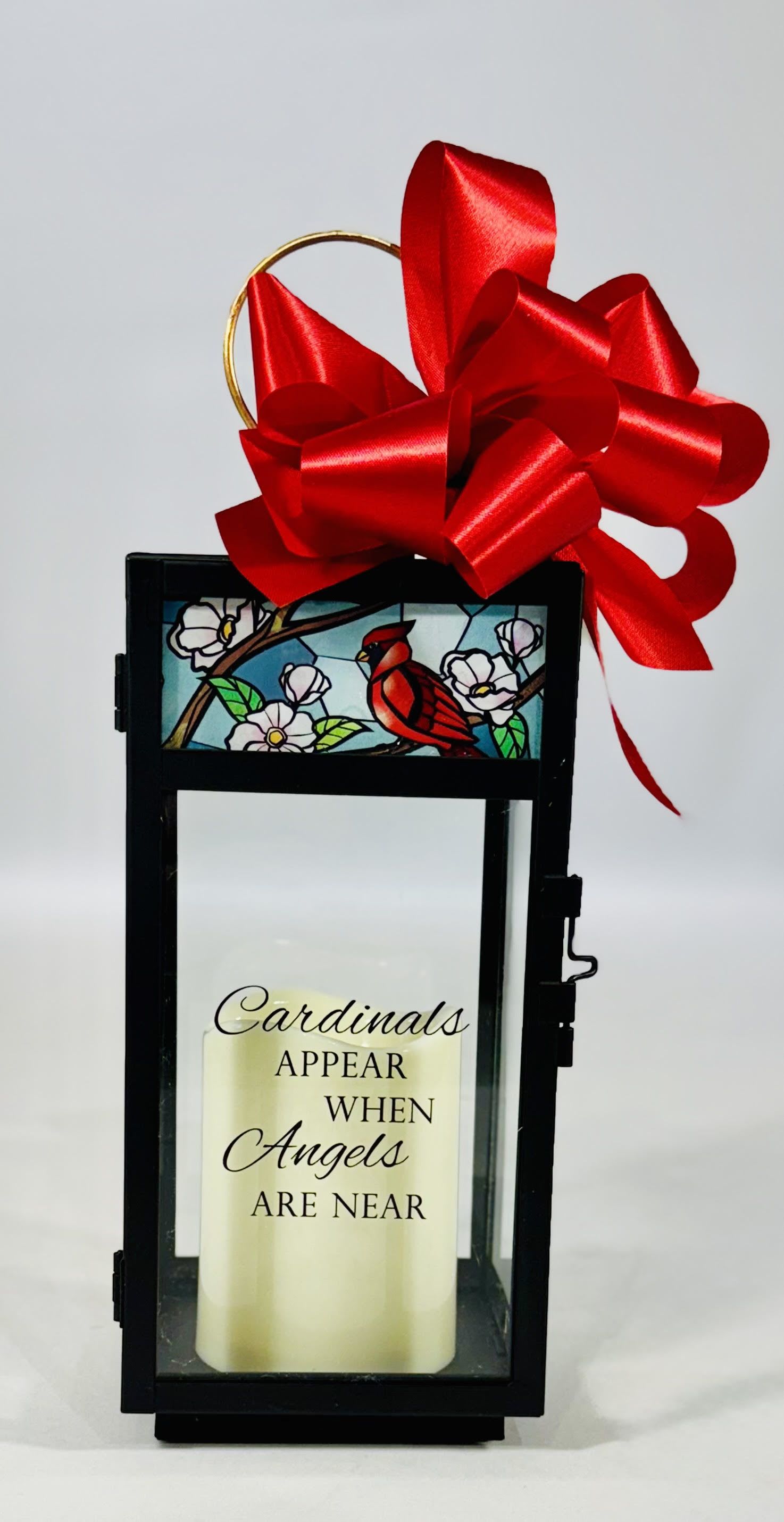 "Cardinals Appear" Stained Glass Top Lighted Lantern - Our stained glass lanterns are made with high-quality black finish. They come inscribed with sentimental quotes amid beautiful stained glass style artwork and a charming flameless LED candle. Suitable for hanging or use as a freestanding item. Recommended as an accent in floral arrangements for many occasions. They are weather friendly! 3 AAA batteries are included. Choose deluxe if you would like to add a Silk arrangement on lid of lantern  Lantern Reads: "Cardinals appear when angels are near"  W: 4.25" H: 12" D: 4.25"