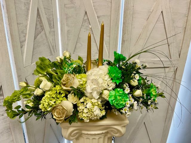 Pot Of Gold - This is the perfect finishing touch to your St. Patrick's Day celebration. A long and low centerpiece with 2 gold candles, Bells Of Ireland, green and white Hydrangea, and more!