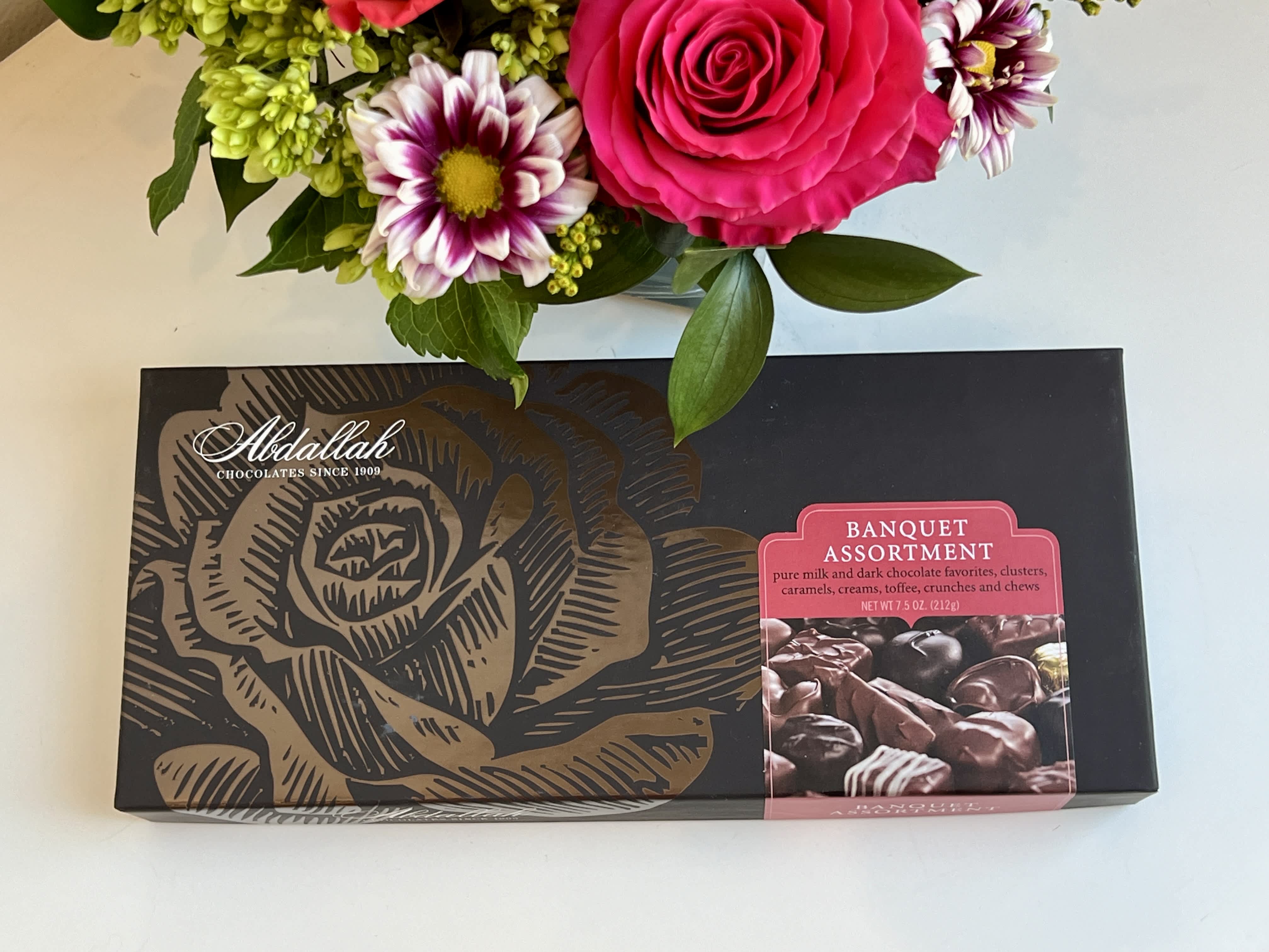 Bouquet above a box of assorted chocolates