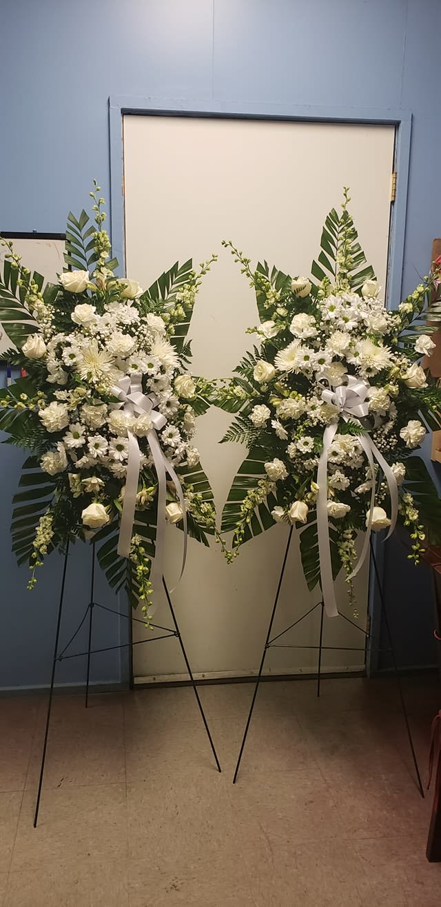 Two white floral standing sprays on easels with ribbon bows