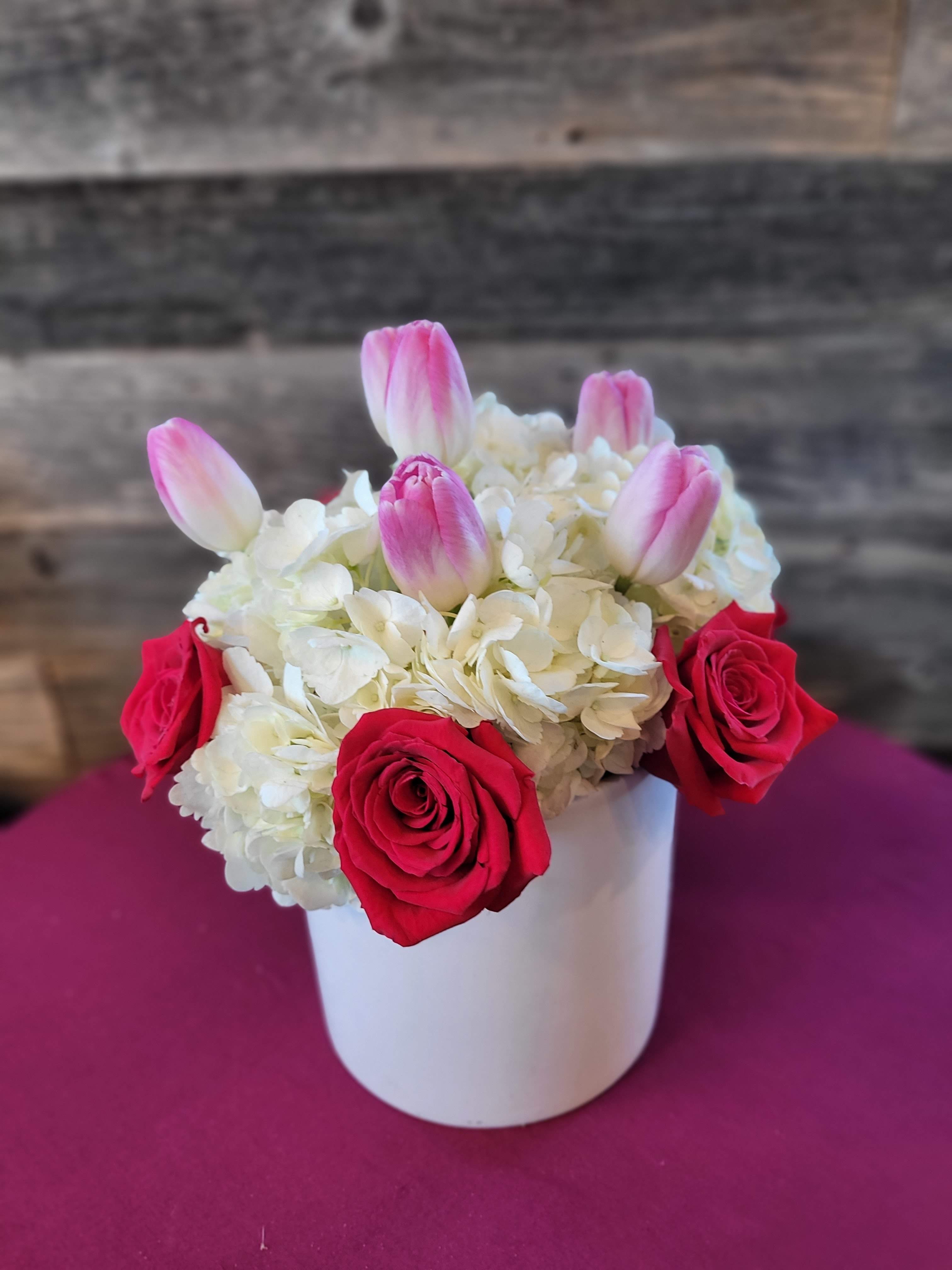 With Love - The perfect gift for that special someone .  Arrangement Details:  This arrangement includes  roses,  tulips, and white hydrangea in a white cylinder vase.