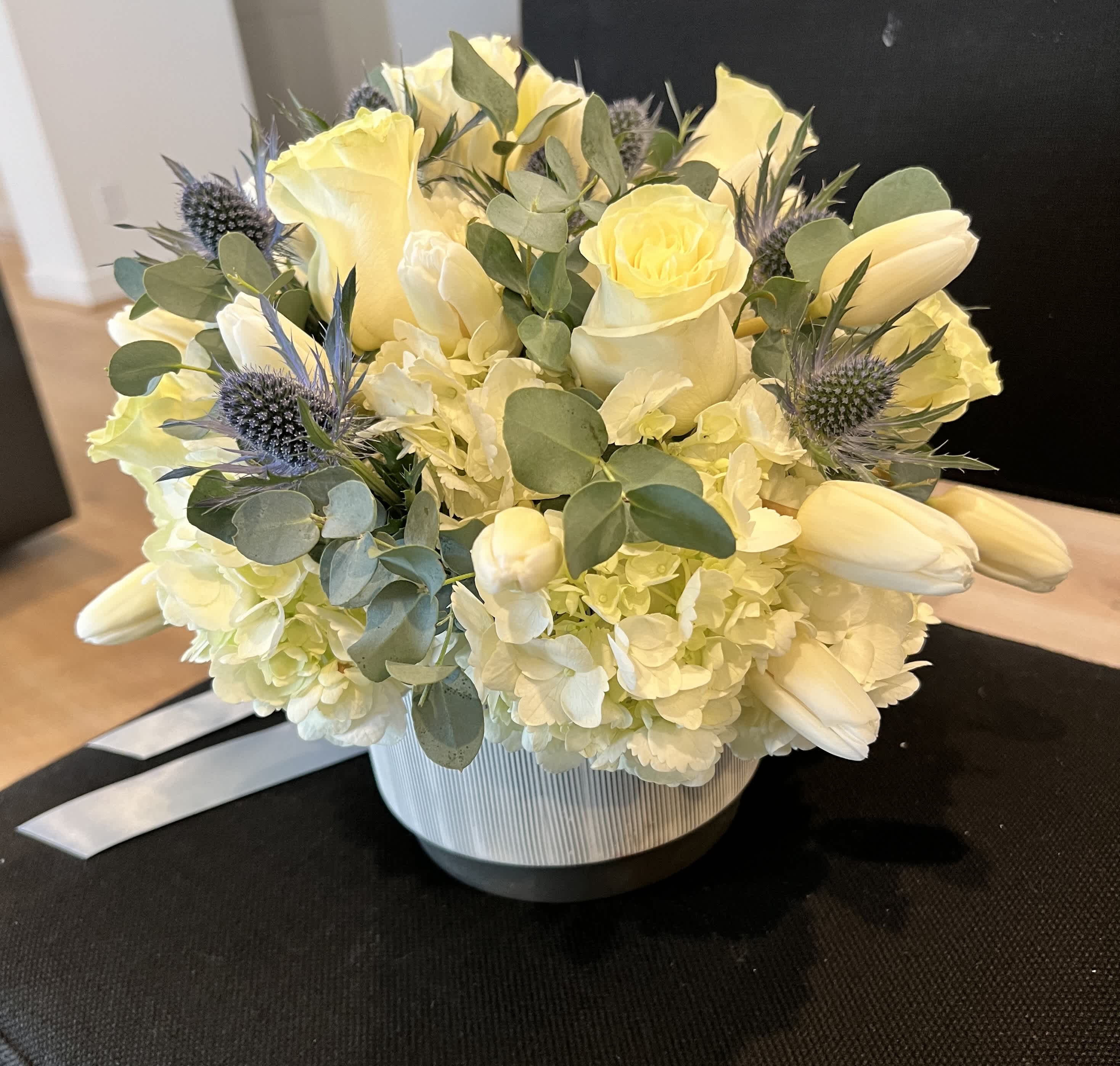 Yellow roses and white tulips arranged in a striped vase