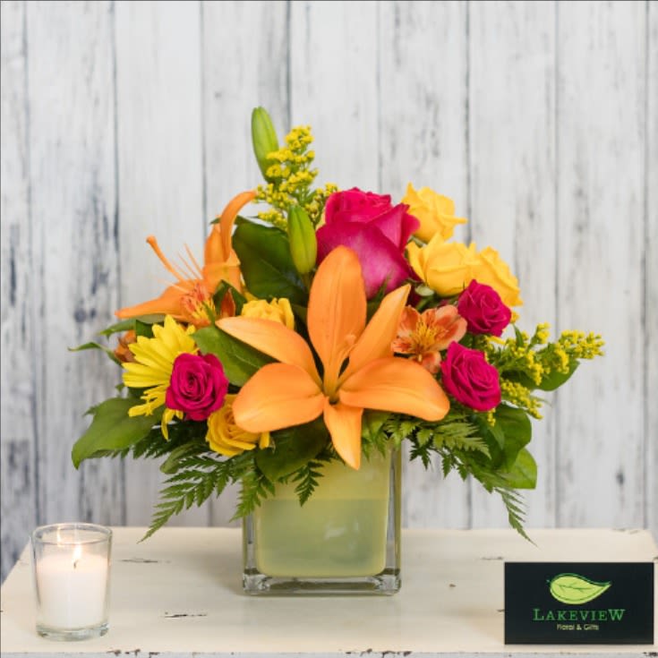 Tangerine - Bright and cheery uplifting blooms in a fun yellow glass cube are sure to brighten anyone's day! This arrangement  includes Asiatic lilies, spray roses, alstroemeria, daisies, and solidago.   Arrangement size is approximately 12" H X 12" W