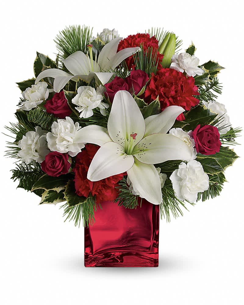 Caroling In The Snow by Teleflora - This festive holiday bouquet includes red roses and white asiatic lilies presented in our red mirrored cube. Red spray roses, white asiatic lilies and red carnations are accented by tips of white pine, noble fir and holly. Delivered in Teleflora's red mirrored cube.
