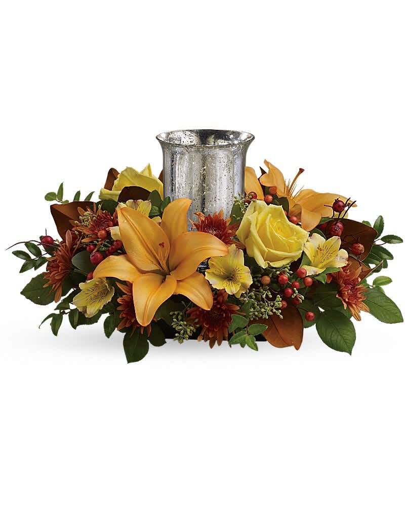 Glowing Gathering Centerpiece by Teleflora - Give a fall gathering a special glow with this wonderfully vibrant autumnal centerpiece, featuring roses and lilies around a shimmering mercury glass hurricane. This beautiful arrangement features yellow roses, peach asiatic lilies, yellow alstroemeria, bronze cushion chrysanthemums, seeded eucalyptus, huckleberry and orange berries. Delivered in an exclusive silver Mercury Glass hurricane.