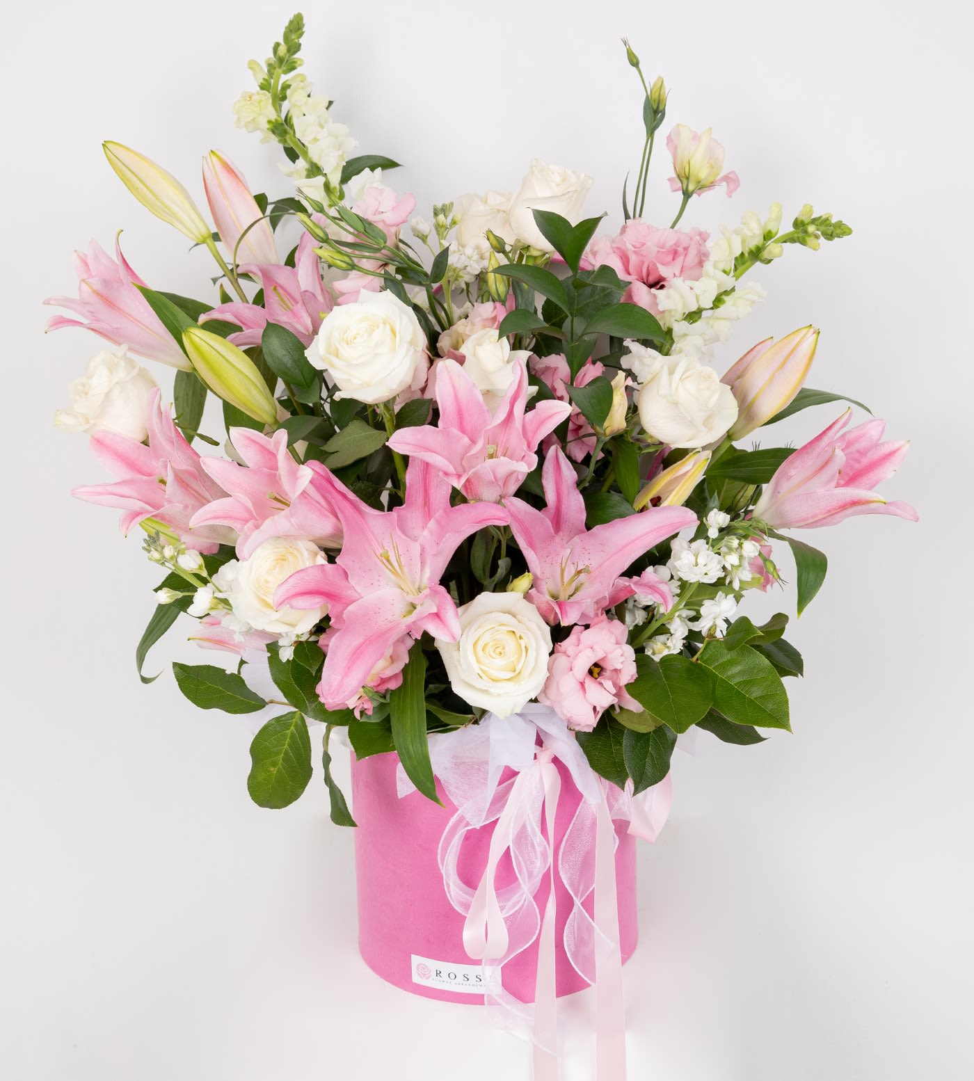 Lily's Bloom - A luxurious large flower box arrangement featuring lilies, white roses, lisianthus, and fresh greenery. Finished with the box lid at the back and accented with an elegant ribbon, making it a perfect gift for any special occasion. Flower selection may vary depending on seasonal availability 