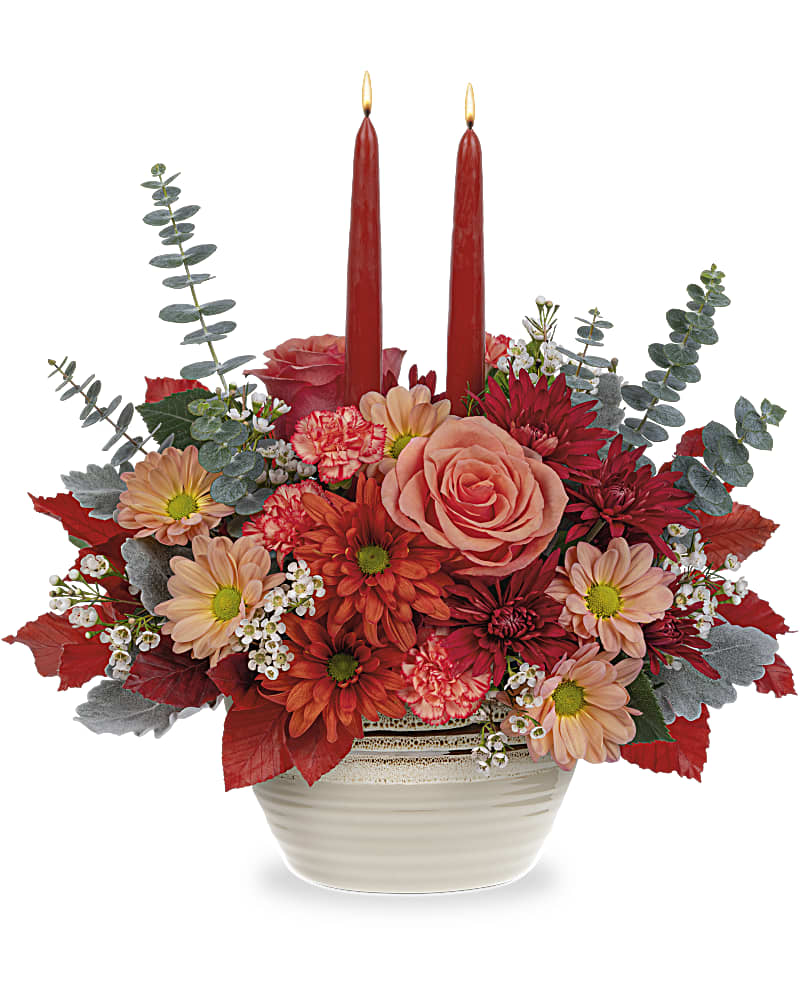 Teleflora's Artisanal Harvest Centerpiece - A stunning centerpiece for all of your fall celebrations, this radiant orange rose bouquet glows beneath elegant tapers in a pretty-meets-practical stoneware serving bowl with gorgeous reactive glaze. Decorate your table this autumn with orange roses, miniature orange carnations, bronze cushion spray chrysanthemums, and white waxflower arranged with red copper beech, spiral eucalyptus and two dark burgundy candles.