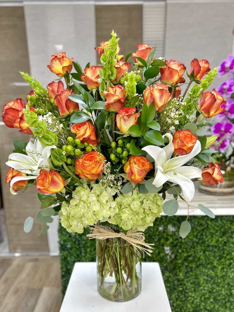 2 Doz. Classic Opened Roses - High Magic Roses - 2 dozen roses (Deluxe) , lilies, green ruscus, solidago aster, and hydrangeas completed with a unique cylinder crystal vase 6x12 and a personalized card message.