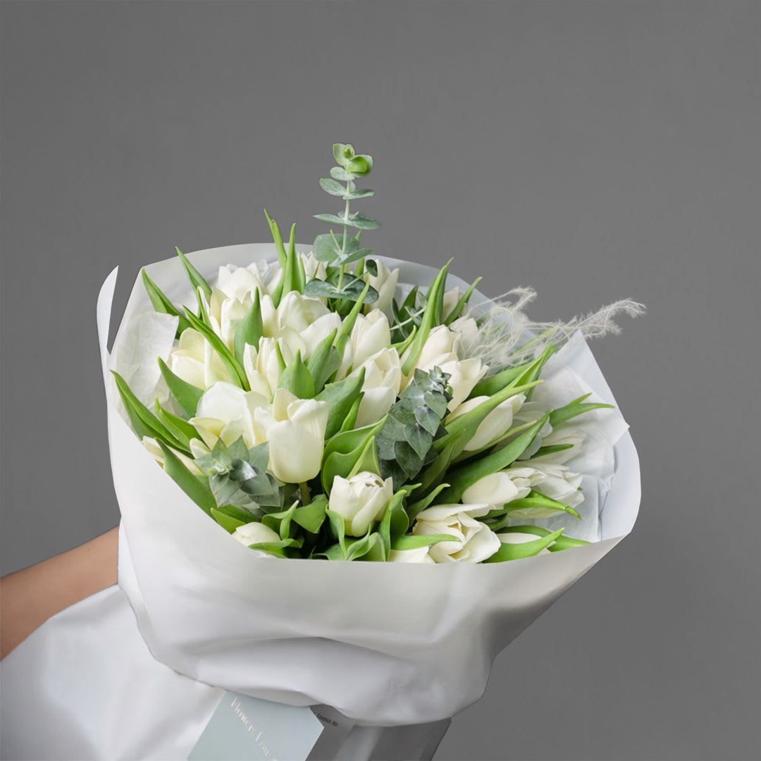 Bouquet of white tulips wrapped in white paper
