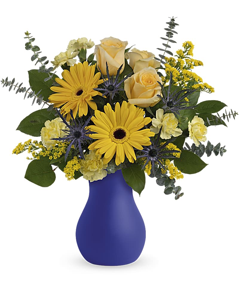 Teleflora's Glorious Morning Bouquet - Bright as the sun in a clear blue sky, this radiant rose and gerbera bouquet is presented to perfection in a cobalt frosted glass vase. This bright arrangement features light yellow roses, yellow gerberas, blue eryngium, miniature yellow carnations, solidago, spiral eucalyptus and lemon leaf. Delivered in Teleflora's Serendipity Glass Vase.