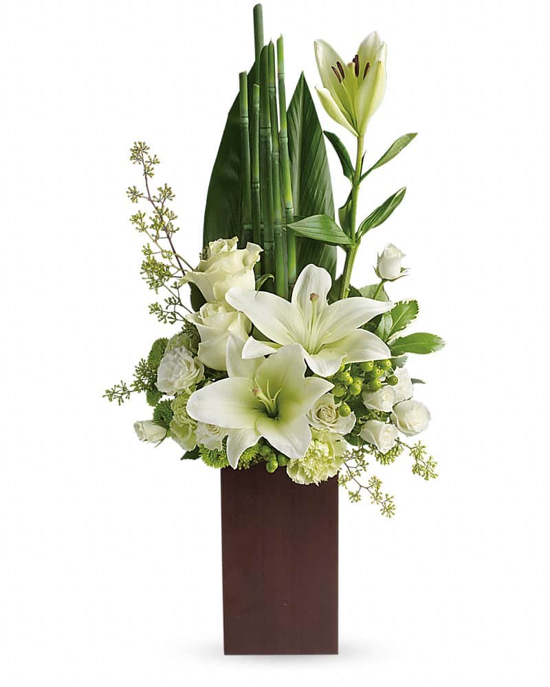 Teleflora's Peace And Harmony Bouquet - Send zen. Pure white blooms and fresh tropical greens combine to stunning effect in this stylish arrangement. Presented in a contemporary bamboo vase they'll enjoy for years to come. Includes white roses, asiatic lilies, green carnations and green button chrysanthemums, accented with a variety of fresh greens. Delivered in a Tall Bamboo vase.