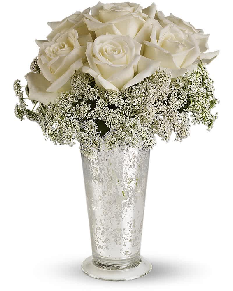 Teleflora's White Lace Centerpiece - Queen Anne's lace forms a delicate collar around radiant white roses inside an antiqued Mercury Glass Vase. Looks lovely next to the wedding guest book, on smaller cocktail tables, or on your beloved wife's boudoir. White roses and Queen Anne's lace are the simple but gorgeous ingredients in this centerpiece, presented in an Mercury Glass Antique Vase.