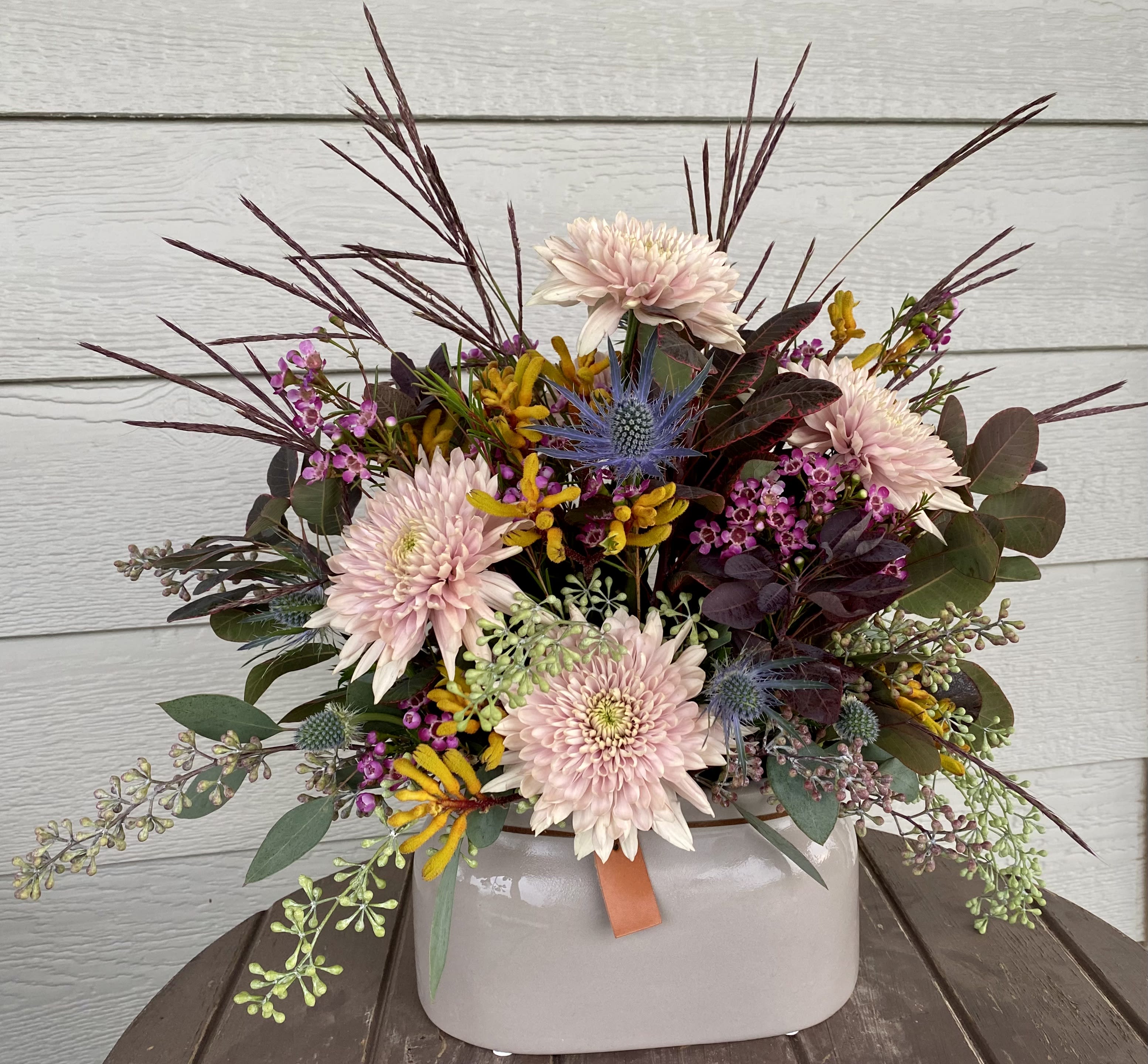 Miss Moe - A delightful combination of rich burgundies and mauves with unique texture.  Including lovely Pink Cremons, Yellow Kangaroo Paw, Blue Thistle, Wax Flower, Smoke Bush, Seeded Eucalyptus, and other greens in a ceramic oval planter.  