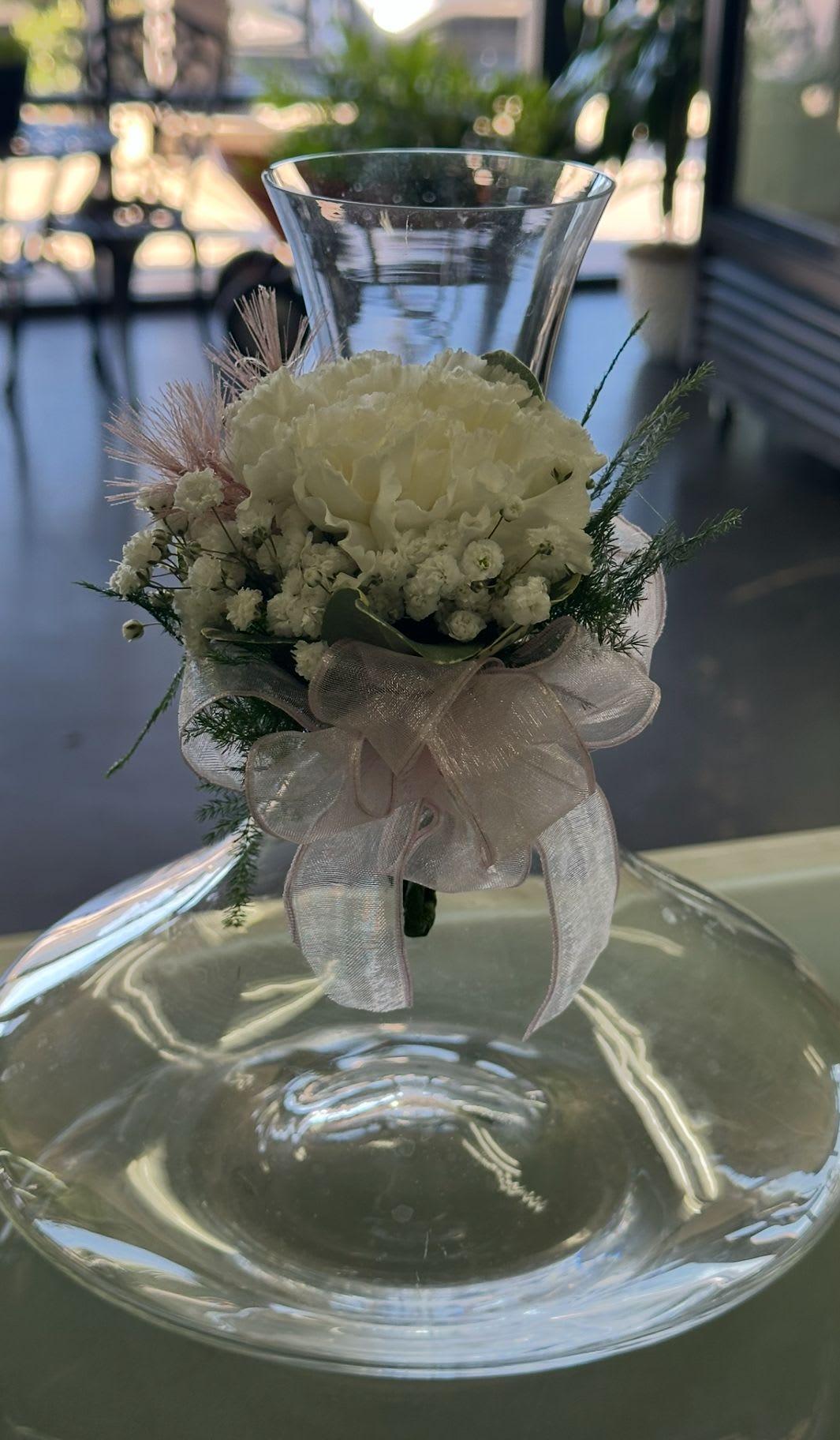 White floral arrangement in a clear glass vase with a sheer ribbon bow
