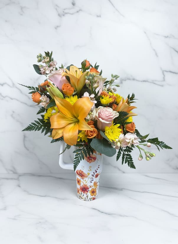 Bouquet of orange lilies, roses, and yellow mums in a floral pitcher vase