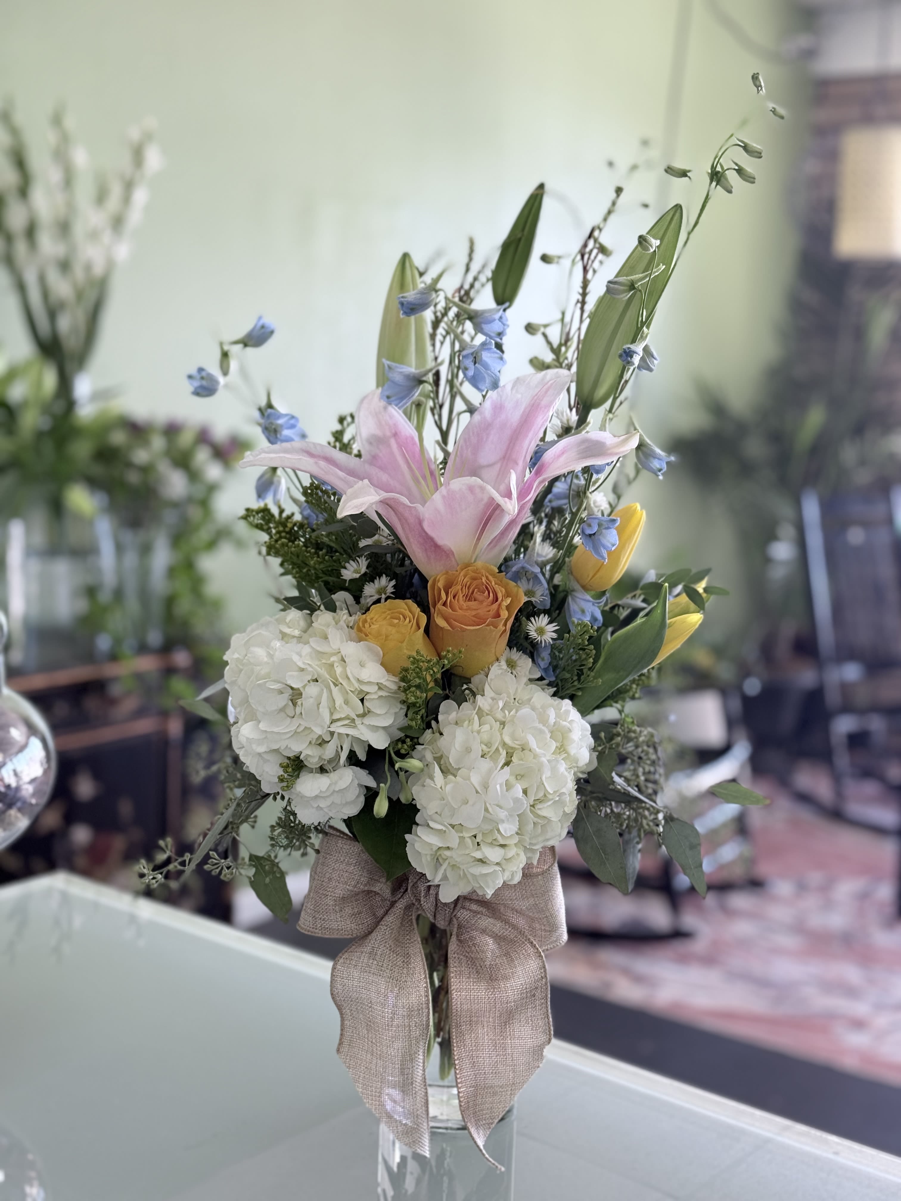 Bouquet of pink lilies, white hydrangeas, and yellow roses in a glass vase