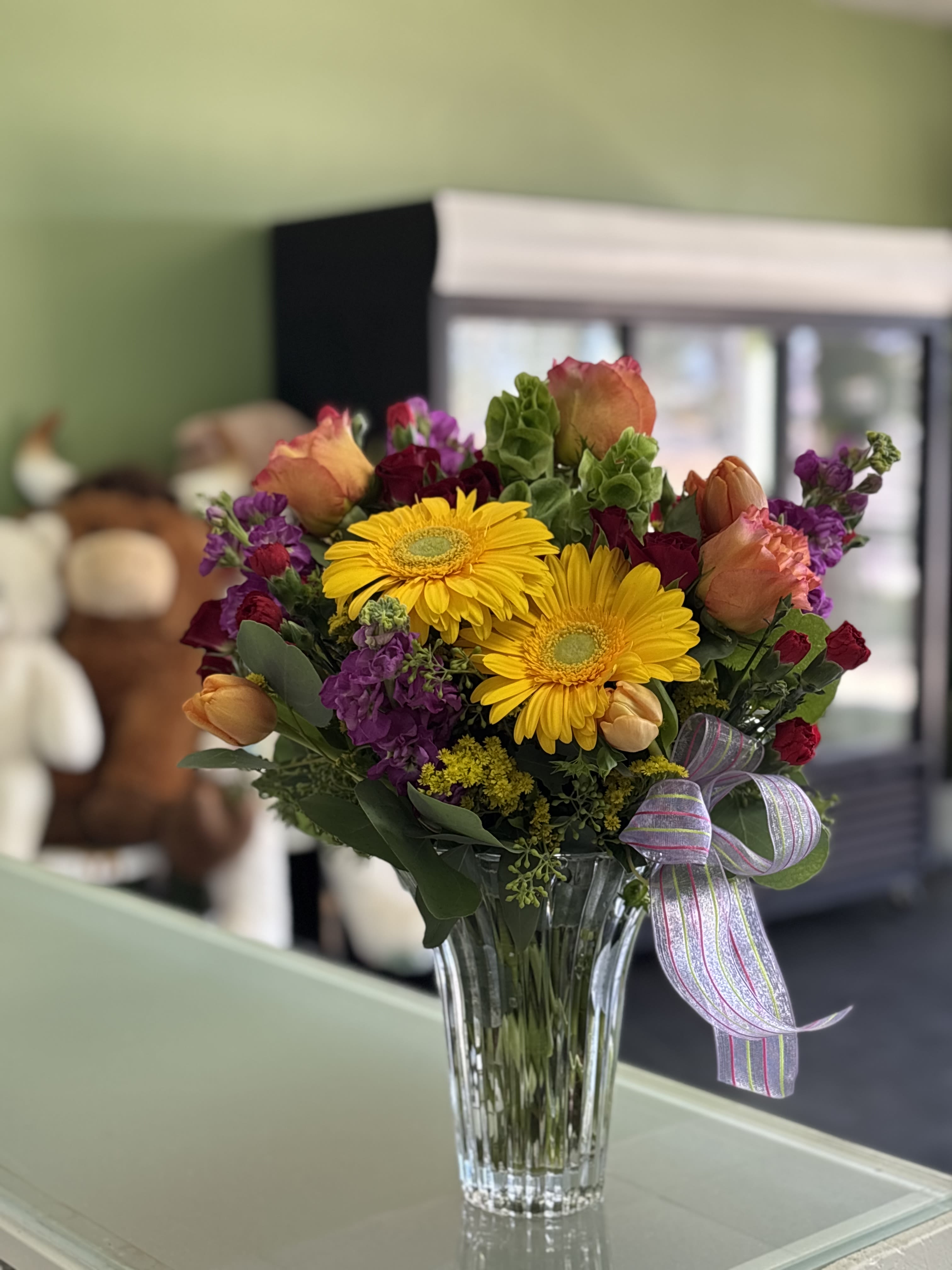 Bouquet of yellow gerbera daisies and mixed roses in a glass vase