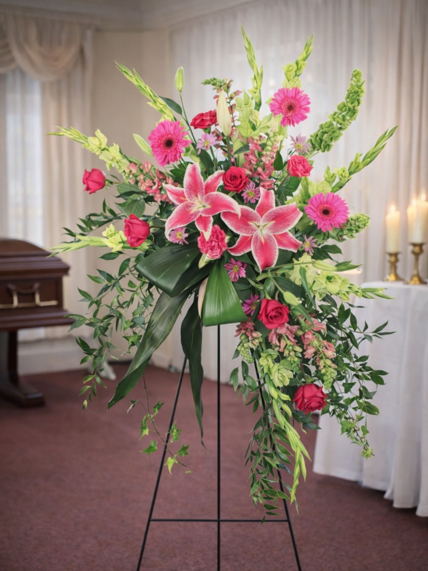 Grateful Heart  Lilies &amp; Roses Standing Spray  - Grateful Heart  Lilies &amp; Roses Standing Spray is a vibrant and heartfelt floral tribute designed to celebrate a cherished life and express deep sympathy. This elegant standing spray features stunning pink stargazer lilies, vibrant pink gerbera daisies, classic red roses, and soft pink accent flowers beautifully arranged among lush greenery and cascading foliage. The graceful design creates a striking vertical display that honors a loved one while offering comfort and remembrance.  Expertly designed by the floral artists at Floral Fabulous, a trusted local florist in Round Rock TX near Austin, this standing spray is an ideal tribute for funeral services, memorial ceremonies, or celebration-of-life gatherings. The fragrant stargazer lilies symbolize remembrance and admiration, while roses represent love and respect for a life well lived. Bright gerbera daisies add warmth and uplifting color to the arrangement.  Displayed on a standing easel, the Grateful Heart Standing Spray creates a meaningful and elegant presence at a funeral or memorial service. Each arrangement is handcrafted using fresh premium flowers to ensure a beautiful tribute that reflects heartfelt sympathy.  Floral Fabulous proudly offers professional funeral flower delivery in Round Rock, Pflugerville, Georgetown, and throughout the greater Austin Texas area.  Grateful Heart Standing Spray is a thoughtful way to honor cherished memories and express sympathy with grace and beauty.