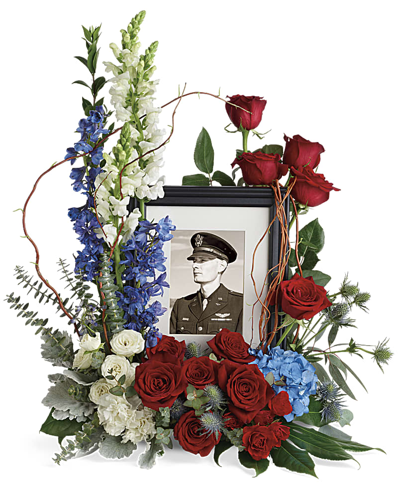 Floral memorial frame with red roses, blue and white flowers, and a black-and-white portrait
