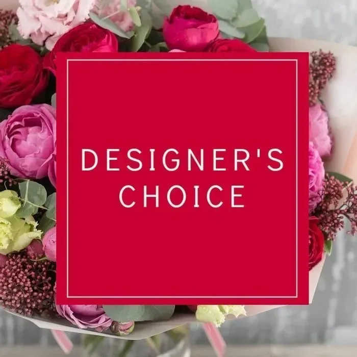 Mixed bouquet of red and pink flowers with a red square label reading Designer's Choice