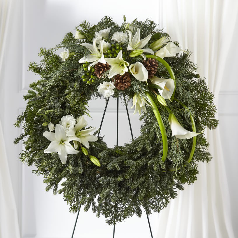 The FTD® Greens of Hope™ Wreath  - Your thoughts, hope and sentiments are captured in this seasonal wreath. The beauty of the rustic Christmas greens and pinecones bring out the purity of the white calla lilies and lisianthus in our Greens of Hope™ Wreath.  Details:   o Wreath is approximately 27" in diameter